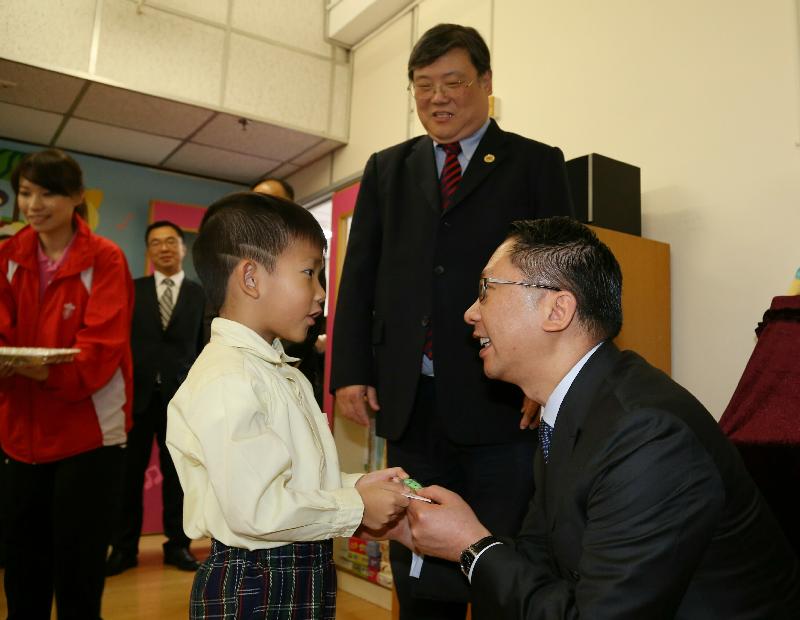 The Secretary for Justice, Mr Rimsky Yuen, SC (right), visited the Hong Kong Lutheran Social Service Martha Boss Lutheran Community Centre and received a souvenir from a kindergarten student at the centre.