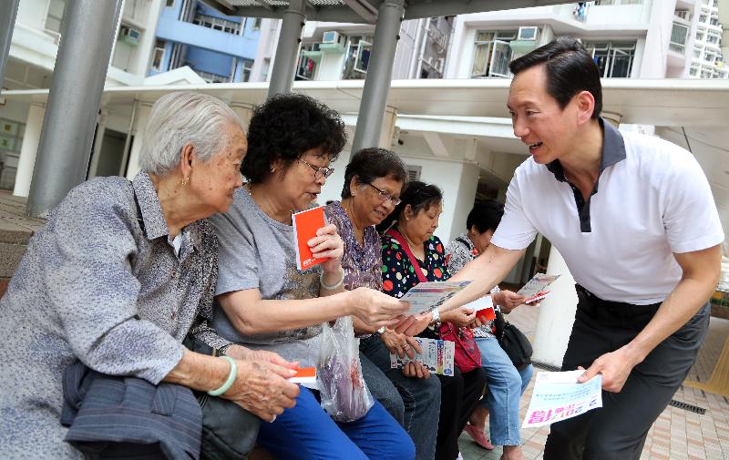 Member of the Executive Council Mr Bernard Chan (right) distributes leaflets to members of the public.
