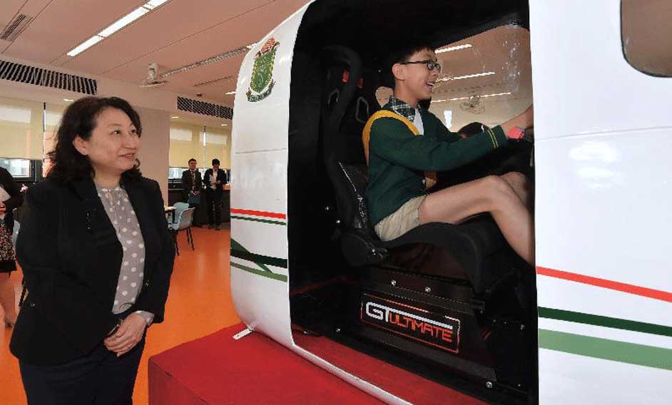 The Secretary for Justice, Ms Teresa Cheng, SC, visited SKH Holy Cross Primary School in Kowloon City today (May 3). Photo shows Ms Cheng (left) observing a student demonstration inside a small aircraft cockpit simulator.