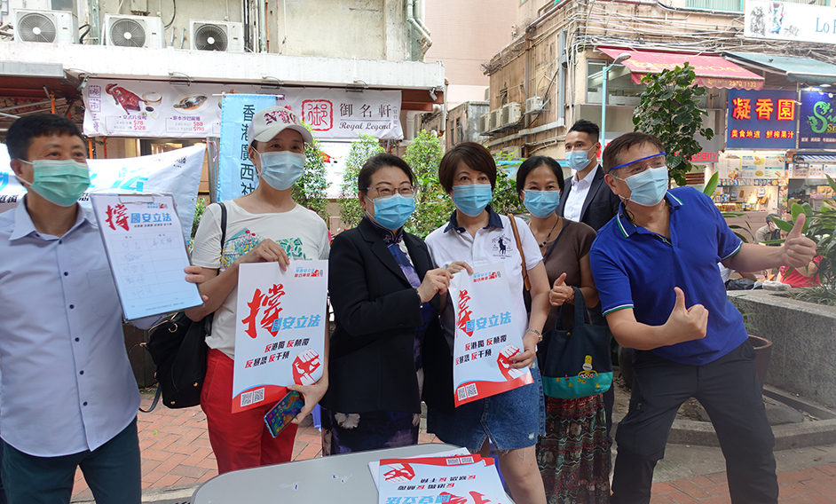 The Secretary for Justice, Ms Teresa Cheng, SC (third left), is pictured with members of public after signing at a street signature campaign today (May 28).